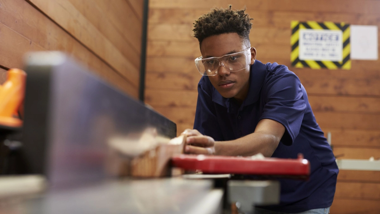 Junger Mann arbeitet in einer Werkstatt mit Holz