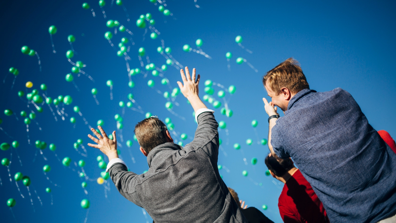 Zwei Menschen mit grünen Luftballons_Symbolbild